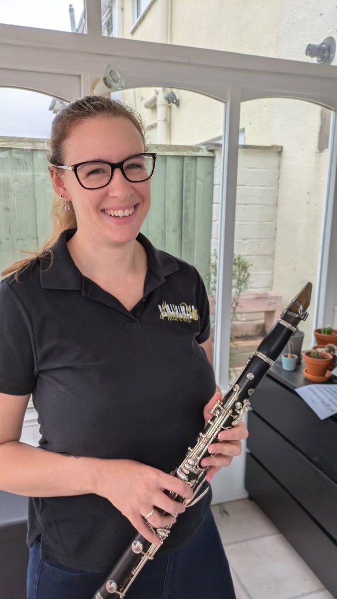 Emma, teacher at Reeds & Keys, smiling and holding a clarinet